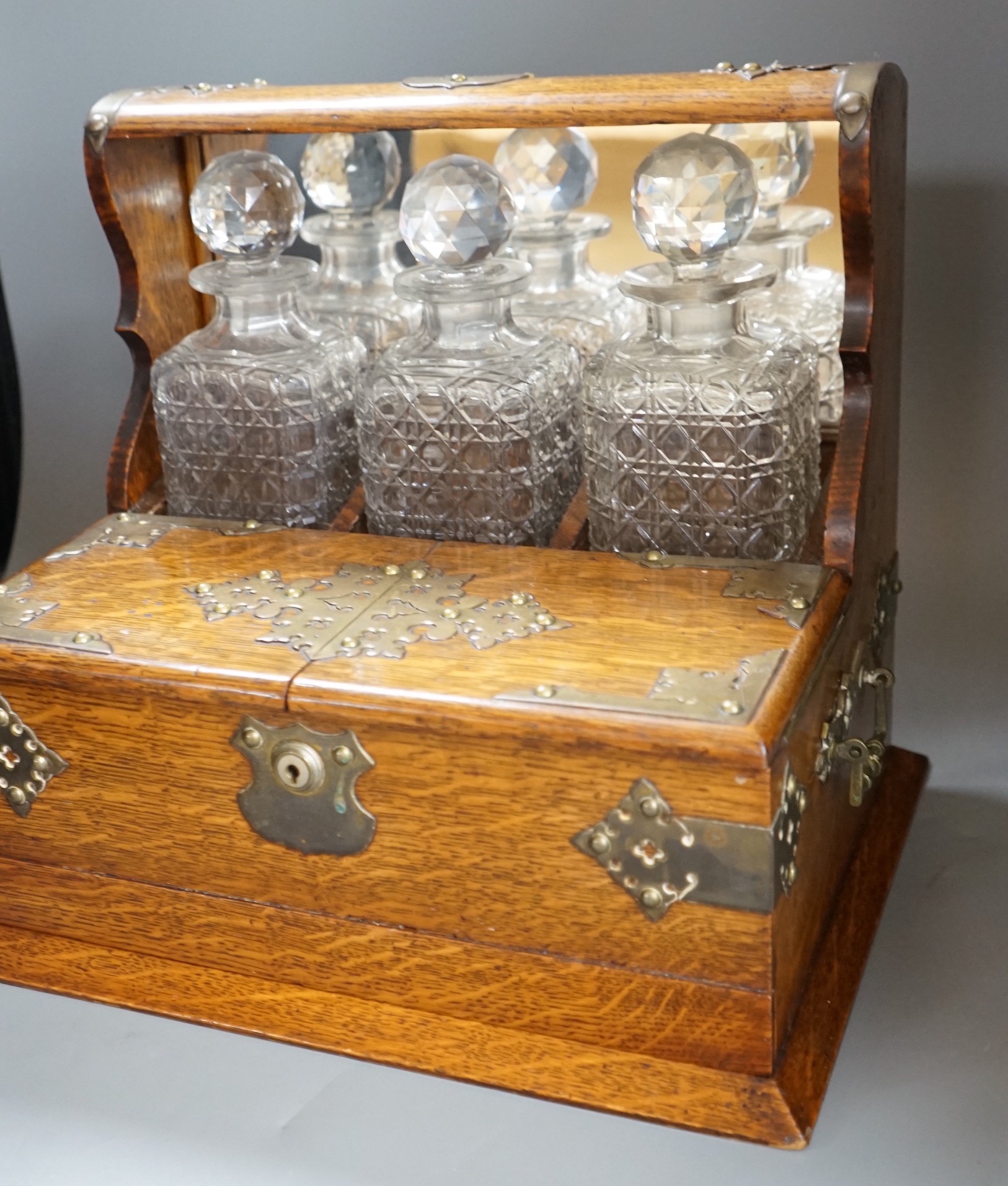 A Victorian brass mounted oak three bottle tantalus, 38cm